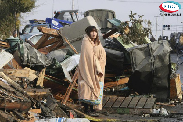 Cô gái đứng nhìn cảnh đổ nát sau trận động đất và sóng thần ngày 11/03/2011