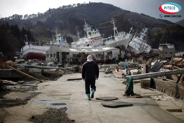 Người đàn ông đi bên cạnh những con tàu sau trận động đất và sóng thần ngày 11/03/2011